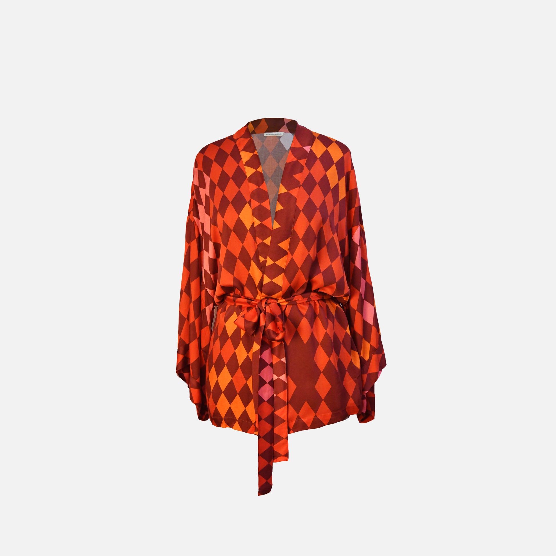 Kimono in warm shades of red, pink, orange and terracotta with belt tied in front view
